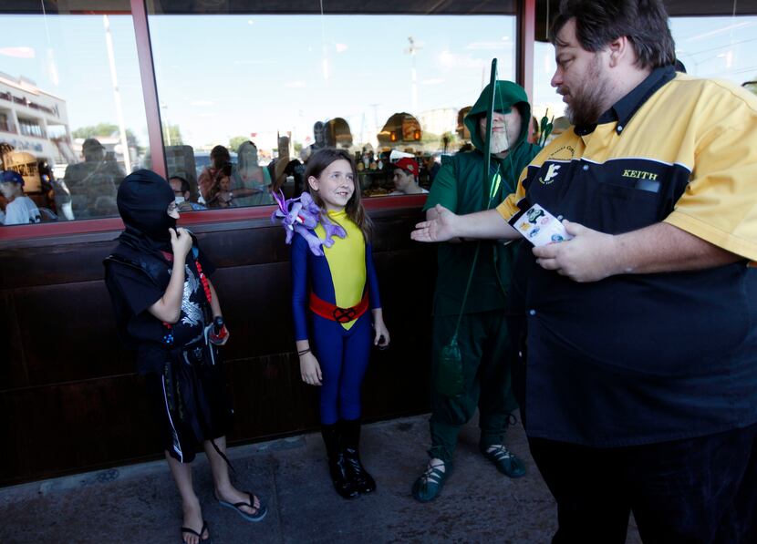 Keith Colvin, right, owner of Keith's Comics awarded Reese Kirkham, 9, of Dallas, dressed as...