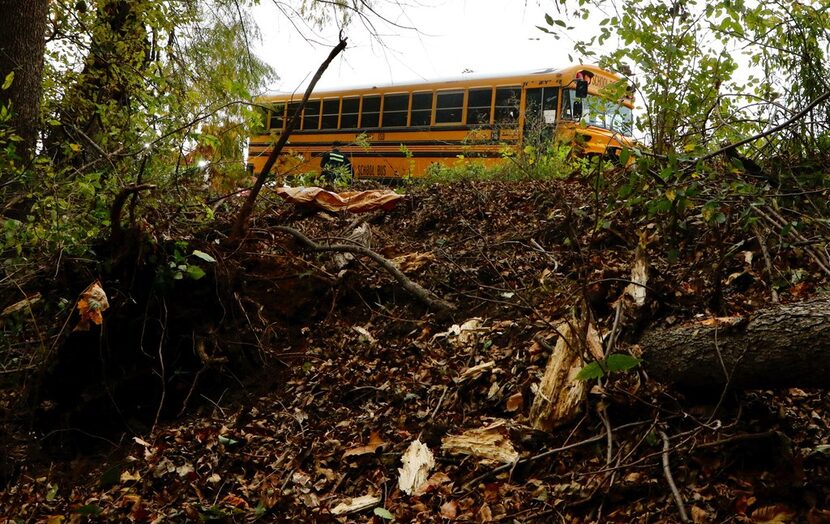 Kevin Macauley of Roper's Wrecker Service in McKinney prepares to pull the school bus out of...