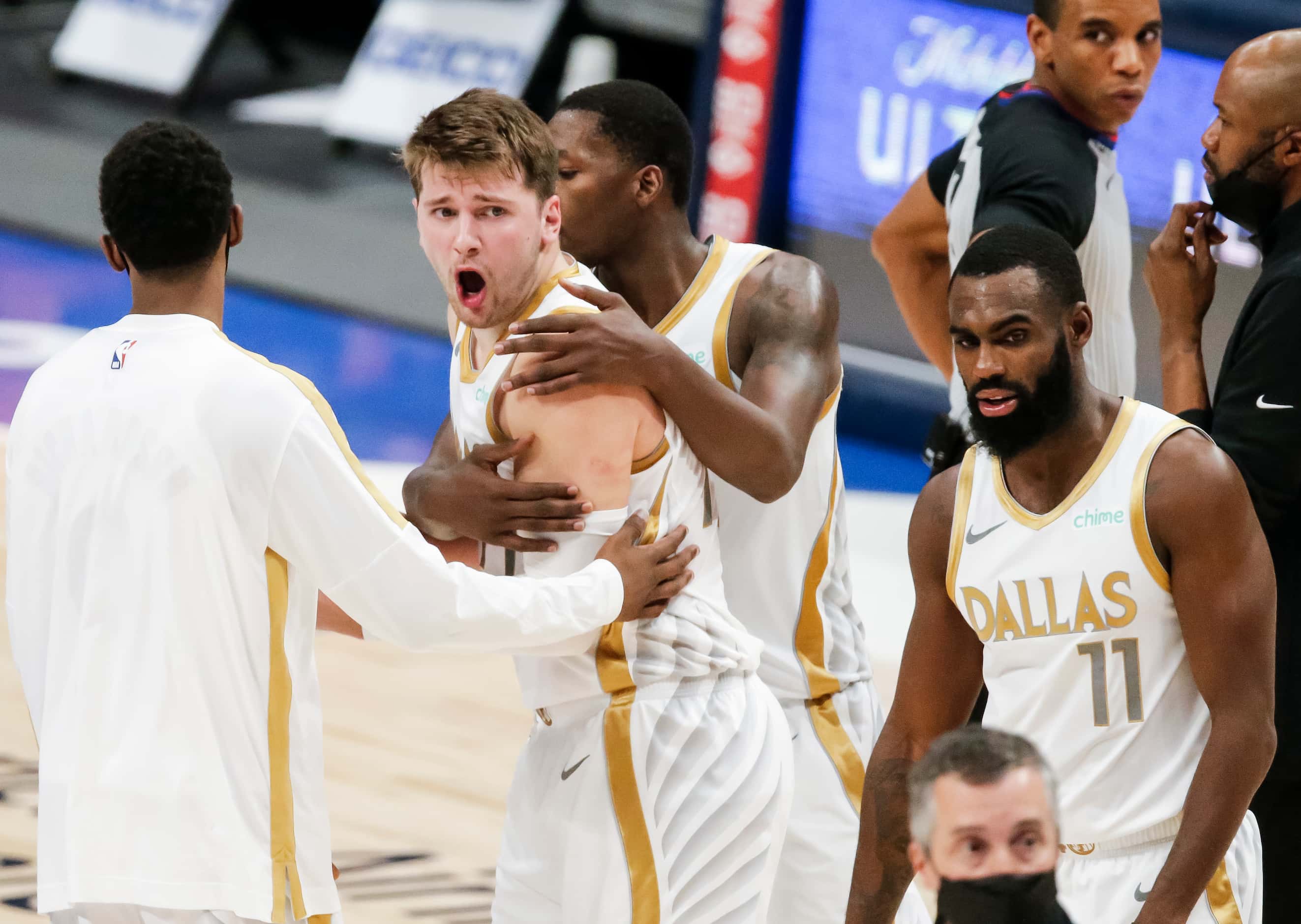Dallas Mavericks guard Luka Doncic (77) is held back by teammates while arguing a call at...