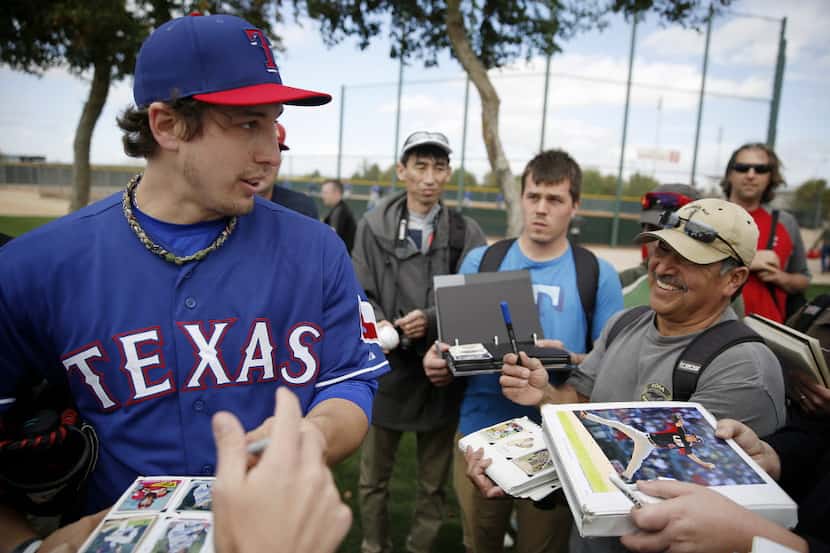 Texas Rangers pitcher Derek Holland (45) signs his autograph for seekers following a workout...
