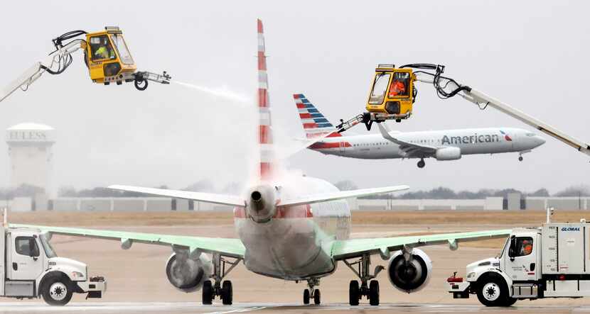 Equipos trabajan para quitar el hielo de una aeronave de American Airlines en el DFW Airport...