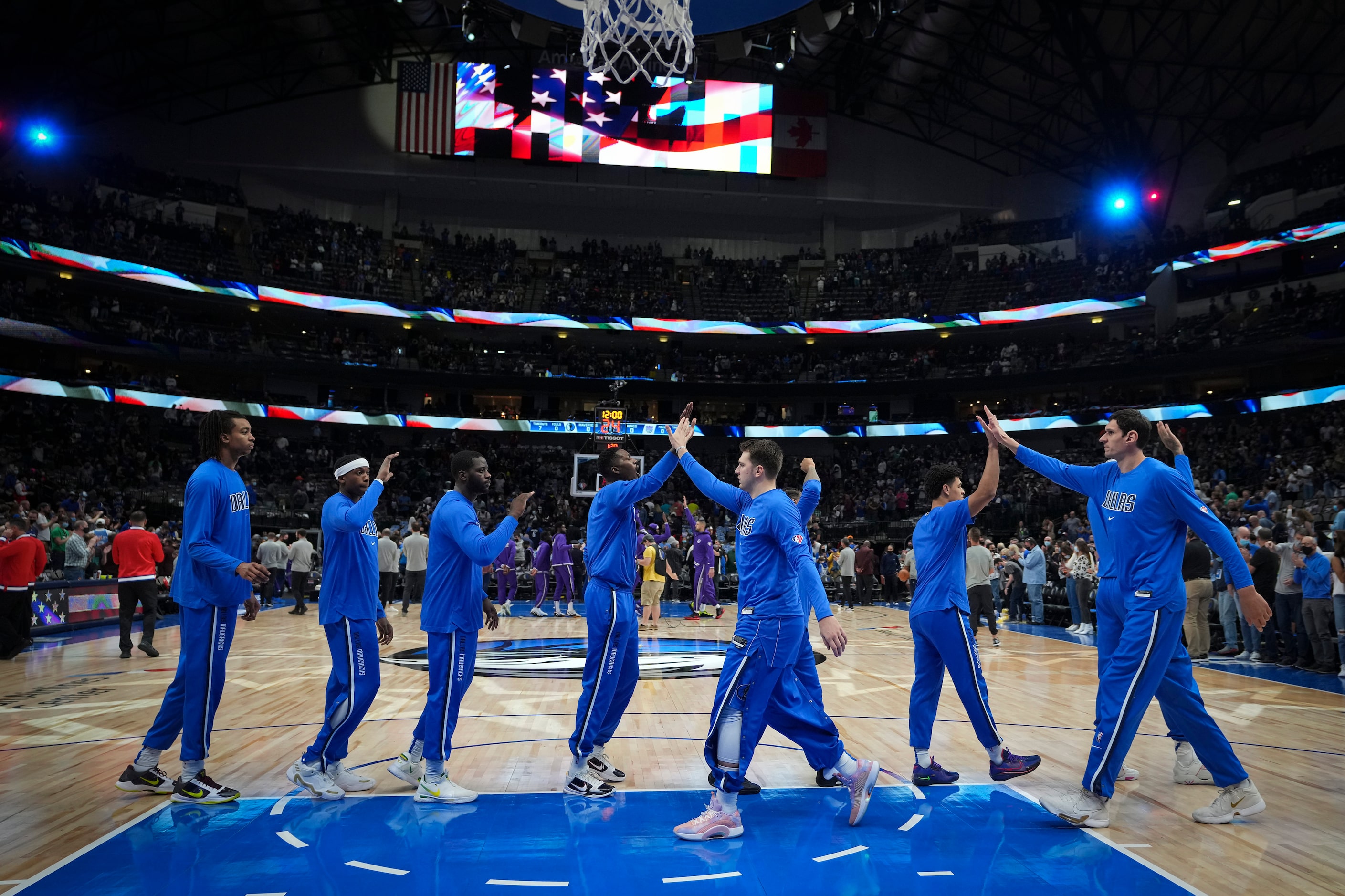 Dallas Mavericks guard Luka Doncic (center) high fives teammates after the playing of the...