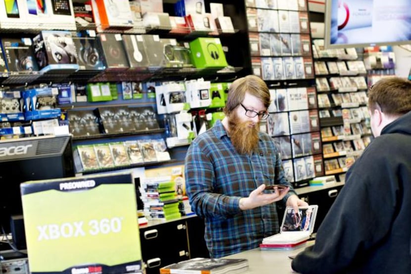 Employee Matt Doyle looks over games being traded in by a customer at a GameStop store in...