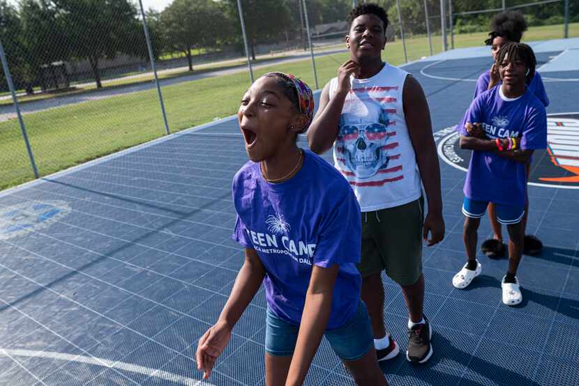 Namoi Robinson, 13, center, reacts after shooting a basketball from the three-point-line...