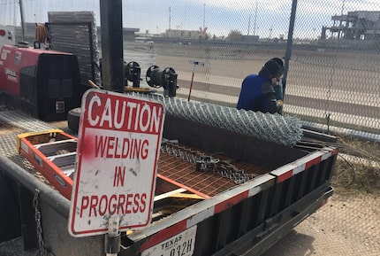 A welding crew repairs holes in the border fence dividing El Paso and Ciudad Juarez almost...