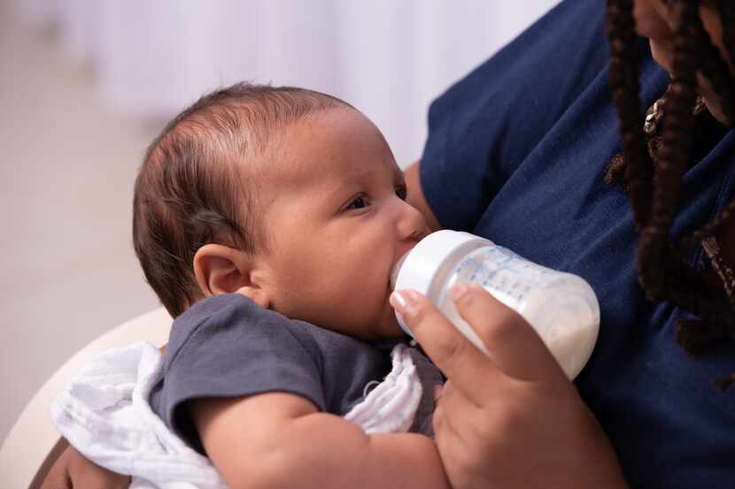 Close-up image of a mother feeding a baby girl with a bottle.