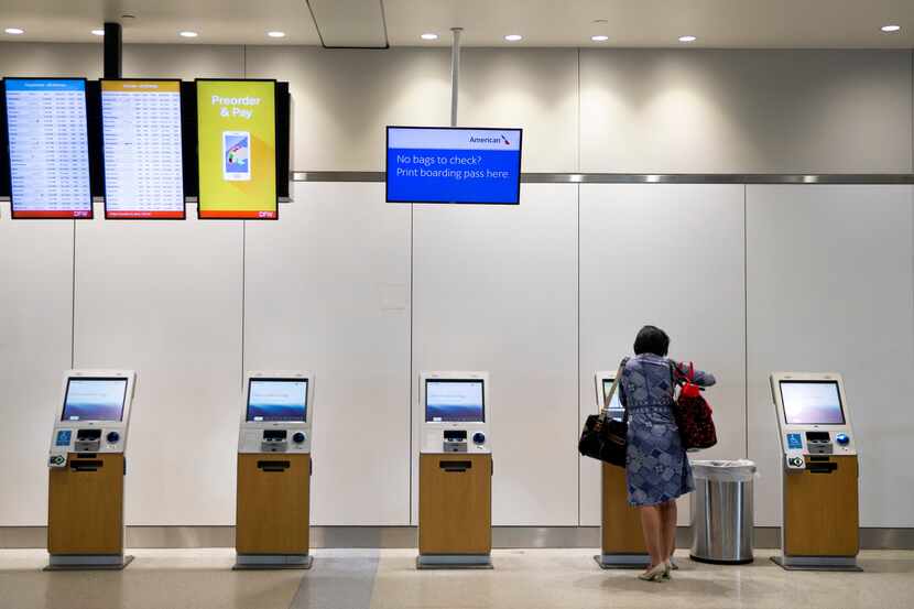 A passenger uses an American Airlines electronic kiosk in the ticketing area of Terminal A...