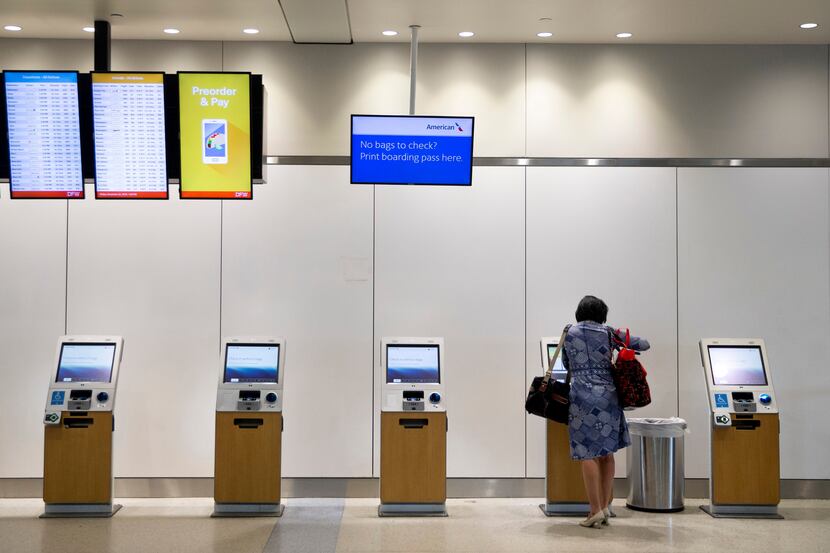 A passenger uses an American Airlines electronic kiosk in the ticketing area of Terminal A...
