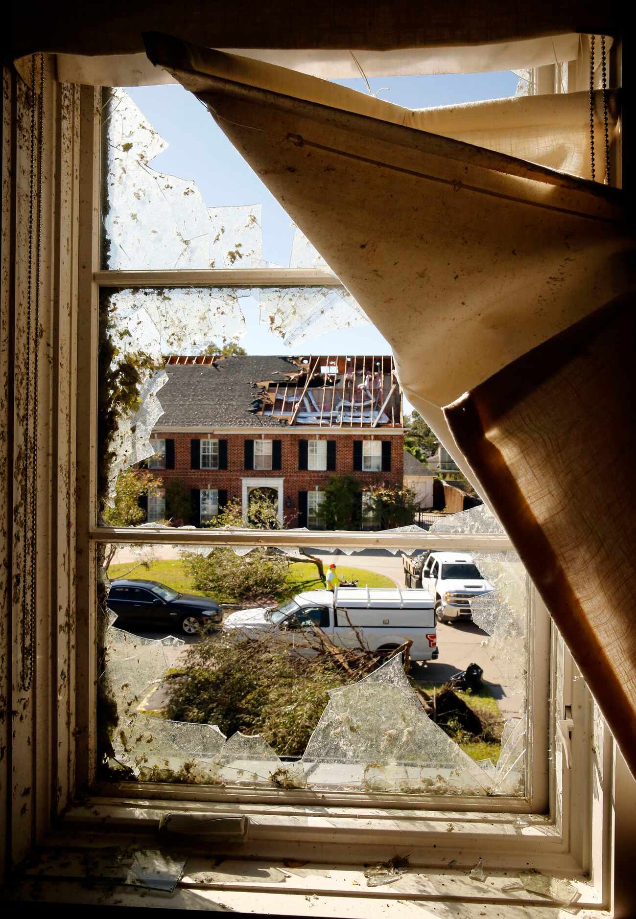 The exposed attic of a damaged house on Pemberton Drive is seen through a broken window at...