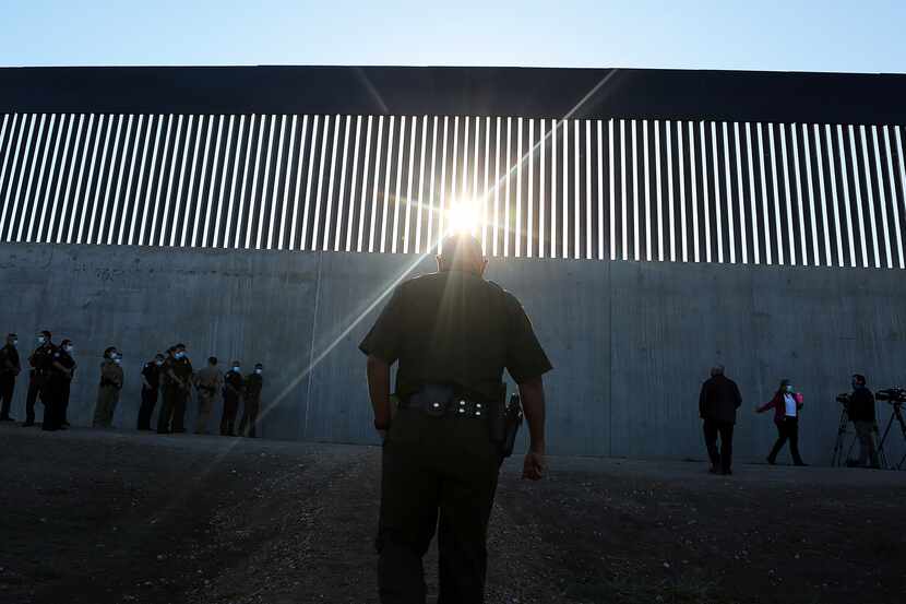 A U.S. Border Patrol agent walk up to a new section of the border wall before the arrival of...