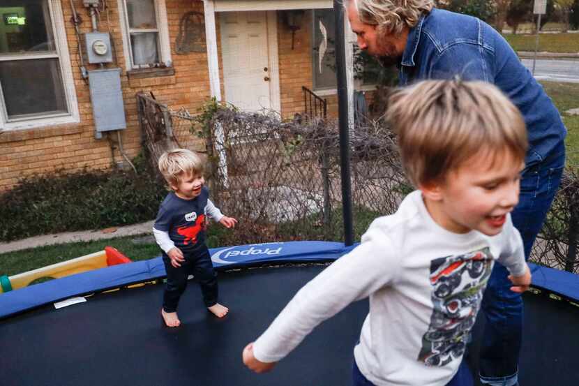 Craig Hoffman plays with his son Roky, 2, as River, 4, jumps next to them on the trampoline...
