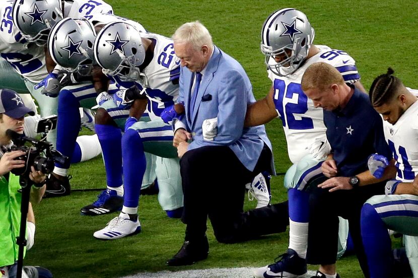 The Dallas Cowboys, led by owner Jerry Jones, center, take a knee prior to the national...