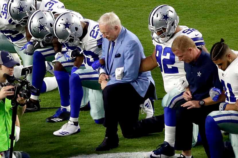 The Dallas Cowboys, led by owner Jerry Jones, center, take a knee prior to the national...