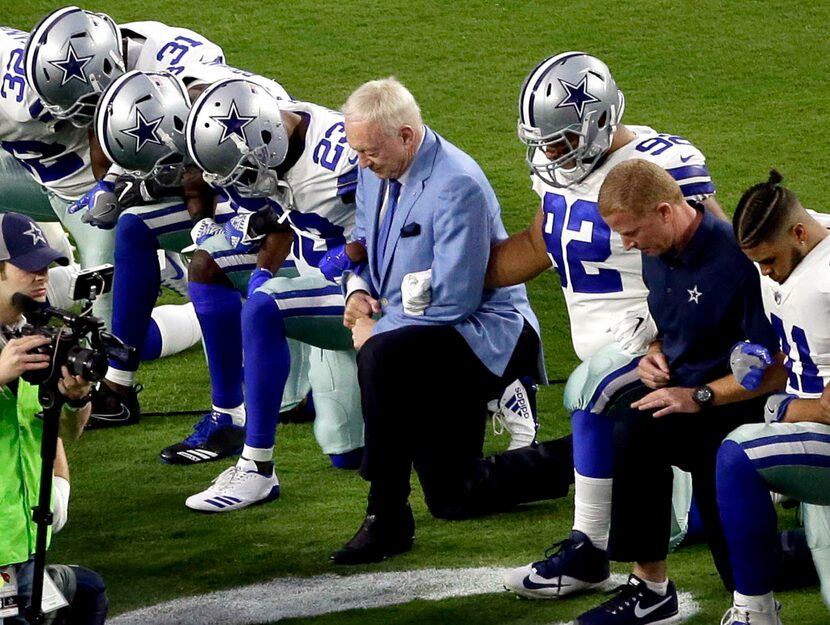 The Dallas Cowboys, led by owner Jerry Jones, center, take a knee prior to the national...