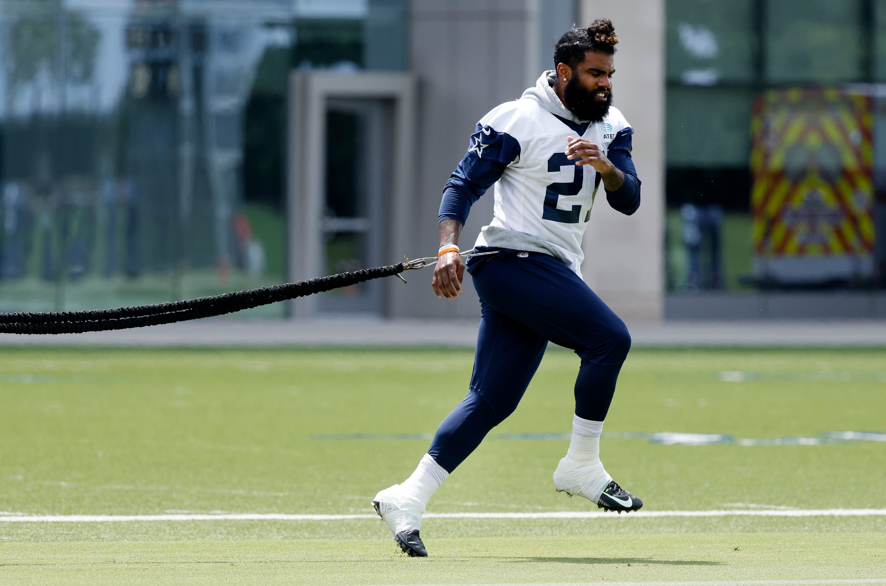 Dallas Cowboys running back Ezekiel Elliott (21) uses a resistance band to stretch before...