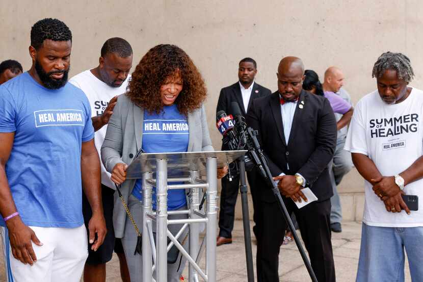 Varonika Wilson with the nonprofit Urban Specialists leads a prayer during a press...