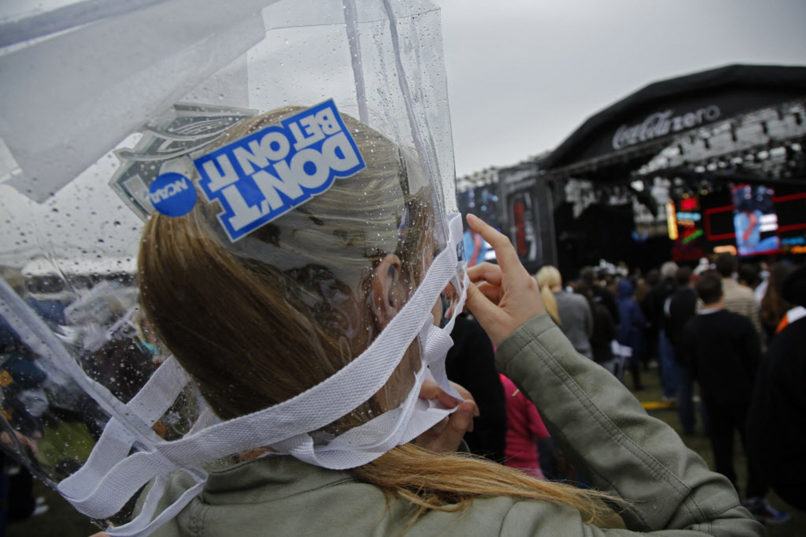 Bethany Canell (cq) wears a clear NCAA bag while light rain hits the March Madness Music...