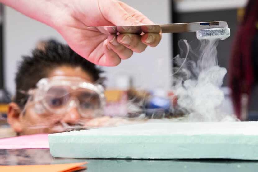 Student George Rosales watches as magnets are used to pick up a superconductor cooled by...