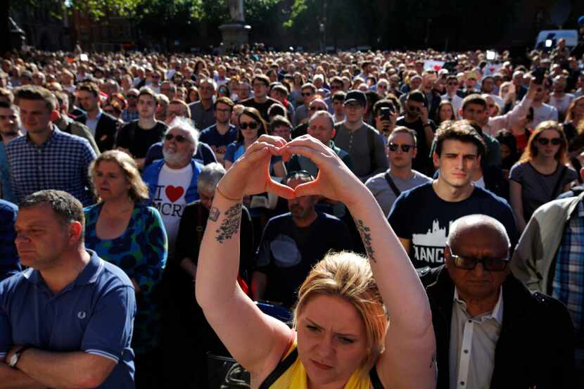 A woman makes a heart gesture as crowds gather for a vigil in Albert Square, Manchester,...