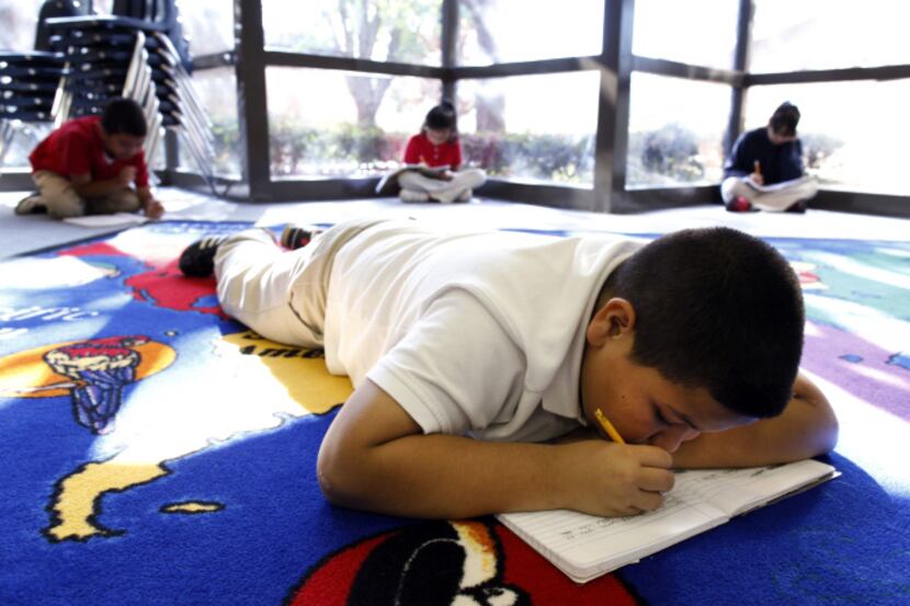 Fourth-grader Jonny Solis writes in his composition book during a writing time in a poetry...