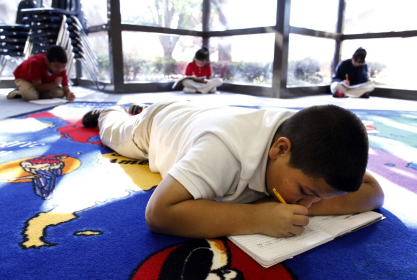 Fourth-grader Jonny Solis writes in his composition book during a writing time in a poetry...