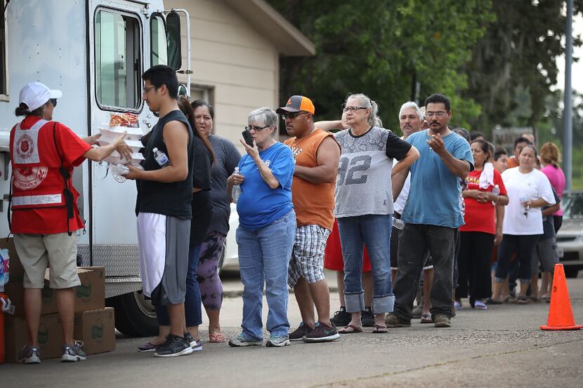 Houston residents line up to receive food and water from a Salvation Army truck after their...