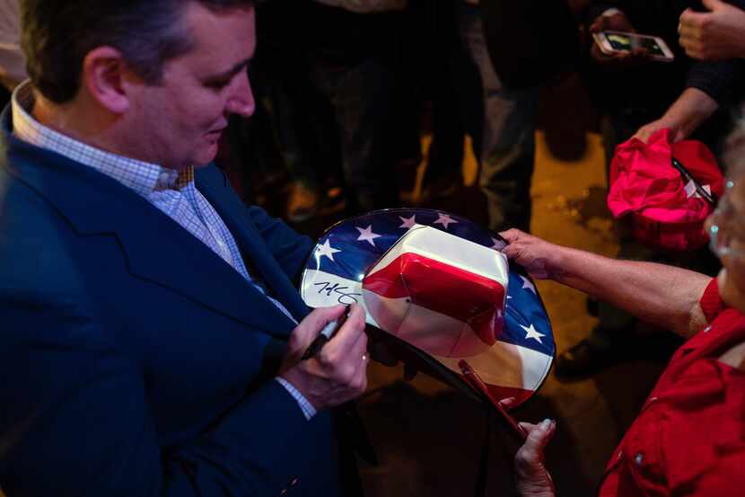 Sen. Ted Cruz (R-Texas) autographs a hat during a campaign rally at  the Creekwood Grill in...
