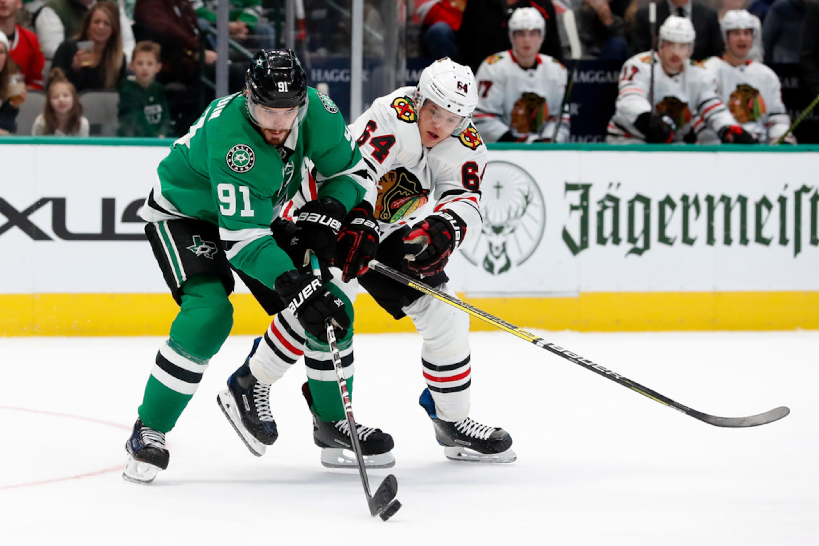 Dallas Stars center Tyler Seguin (91) and Chicago Blackhawks center David Kampf (64) compete...