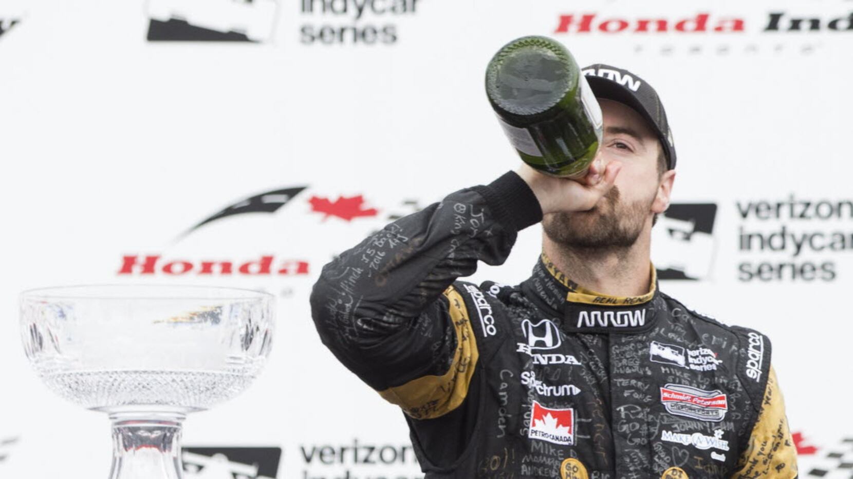Canadian Driver James Hinchcliffe drinks champagne as he celebrates his third place finish...