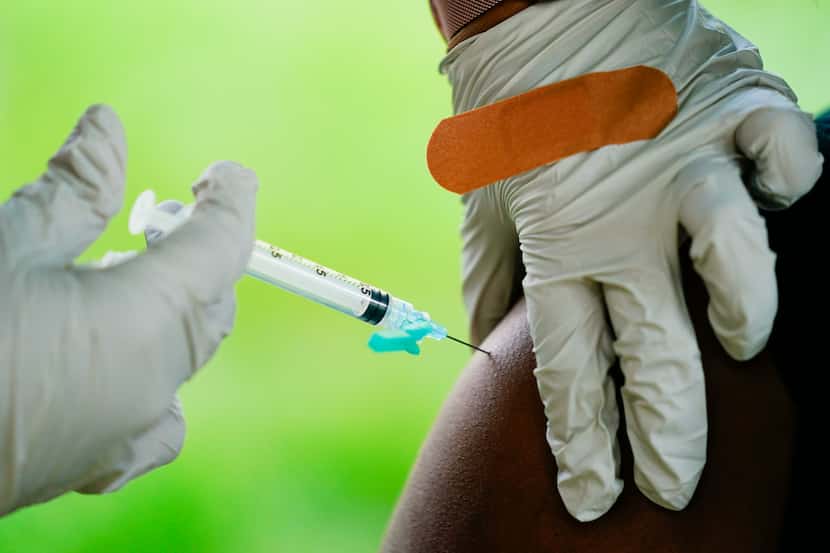 Un trabajador sanitario administra una dosis de la vacuna contra covid-19 de Pfizer en...