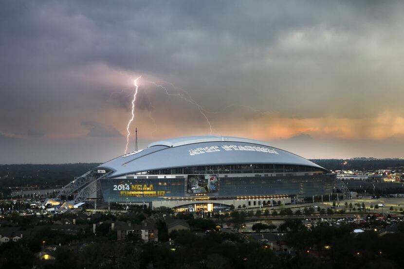 A lightning bolts strike from a passing thunderstorm in S. Arlington behind AT&T Stadium in...