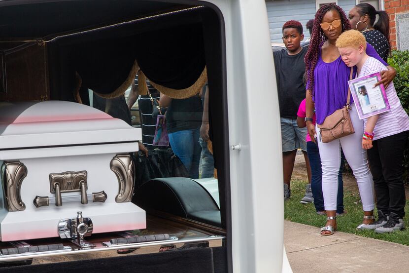 McKenzie Steward (right), 10, is comforted as the coffin of 9-year-old Brandoniya Bennett is...