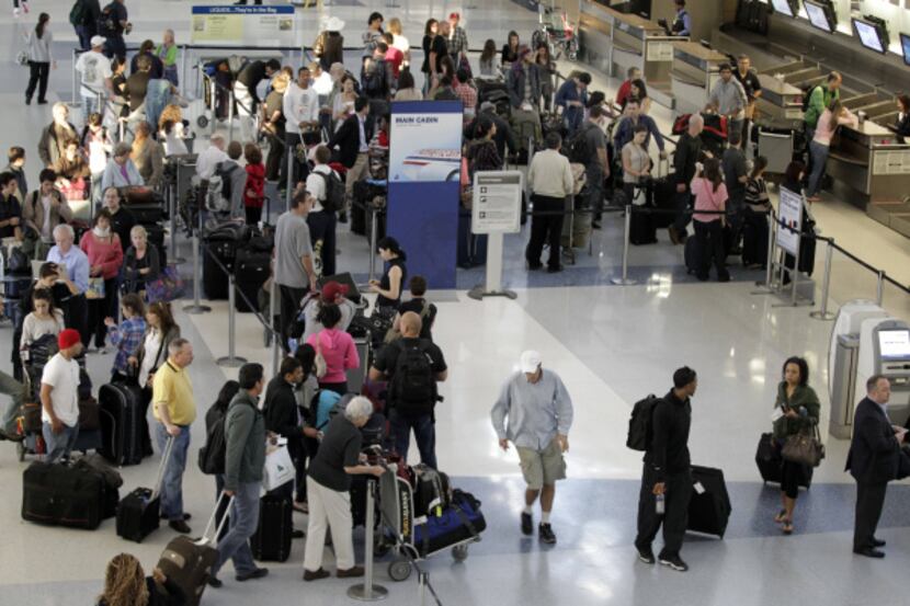 Passengers waited in line at Terminal D at D/FW Airport on Wednesday after American Airlines...