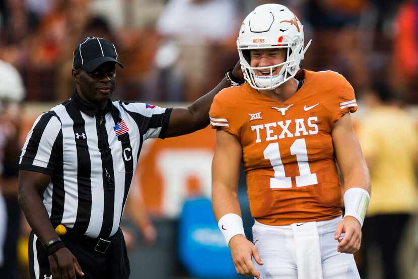 Texas Longhorns quarterback Sam Ehlinger (11) gets a pat on the helmet from an official...
