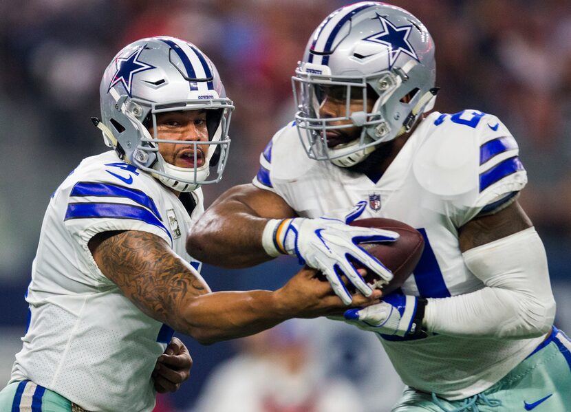 Dallas Cowboys quarterback Dak Prescott (4) hands the ball to running back Ezekiel Elliott...