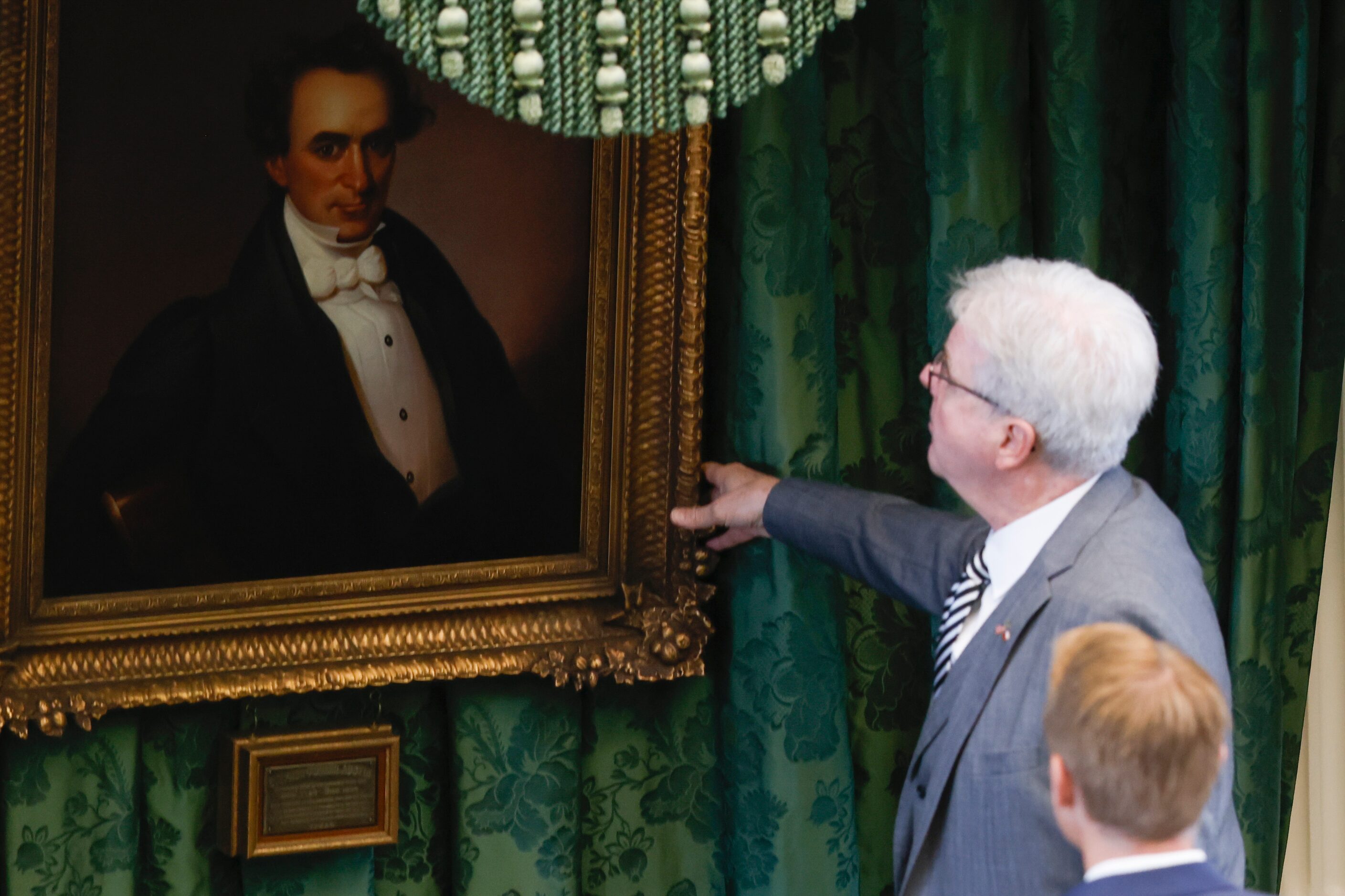 Lt. Gov. Dan Patrick adjusts the portrait of Stephen F. Austin that hangs over the dais...