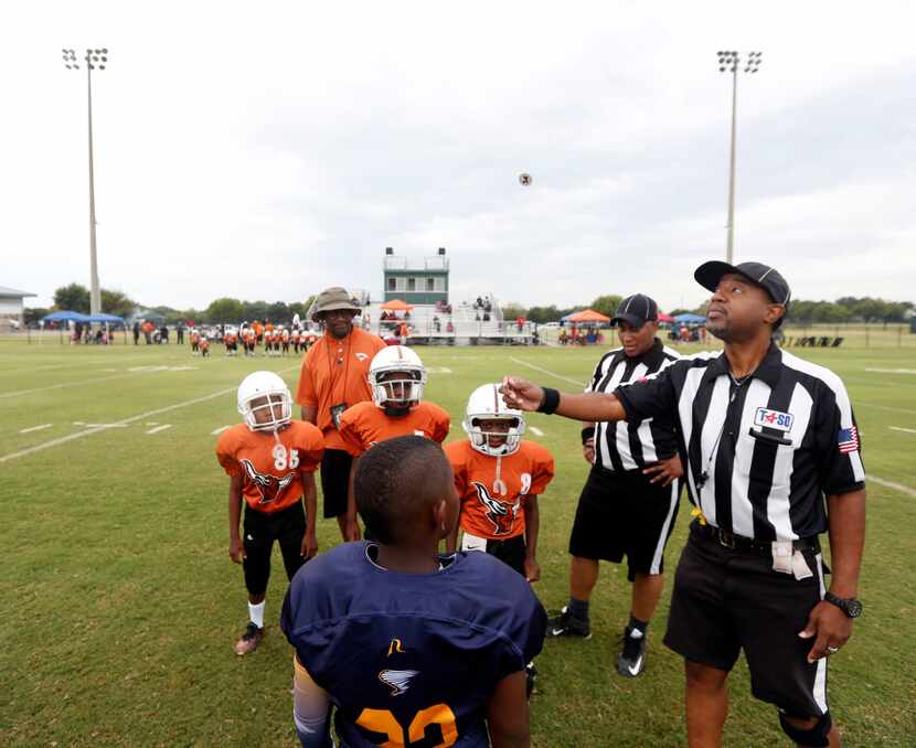 Referee Fred Cox flipped the coin before the start of a youth football game between the...