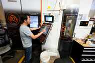 FILE - A worker at Reata Engineering and Machine Works programs a Mazak Variaxis machine...