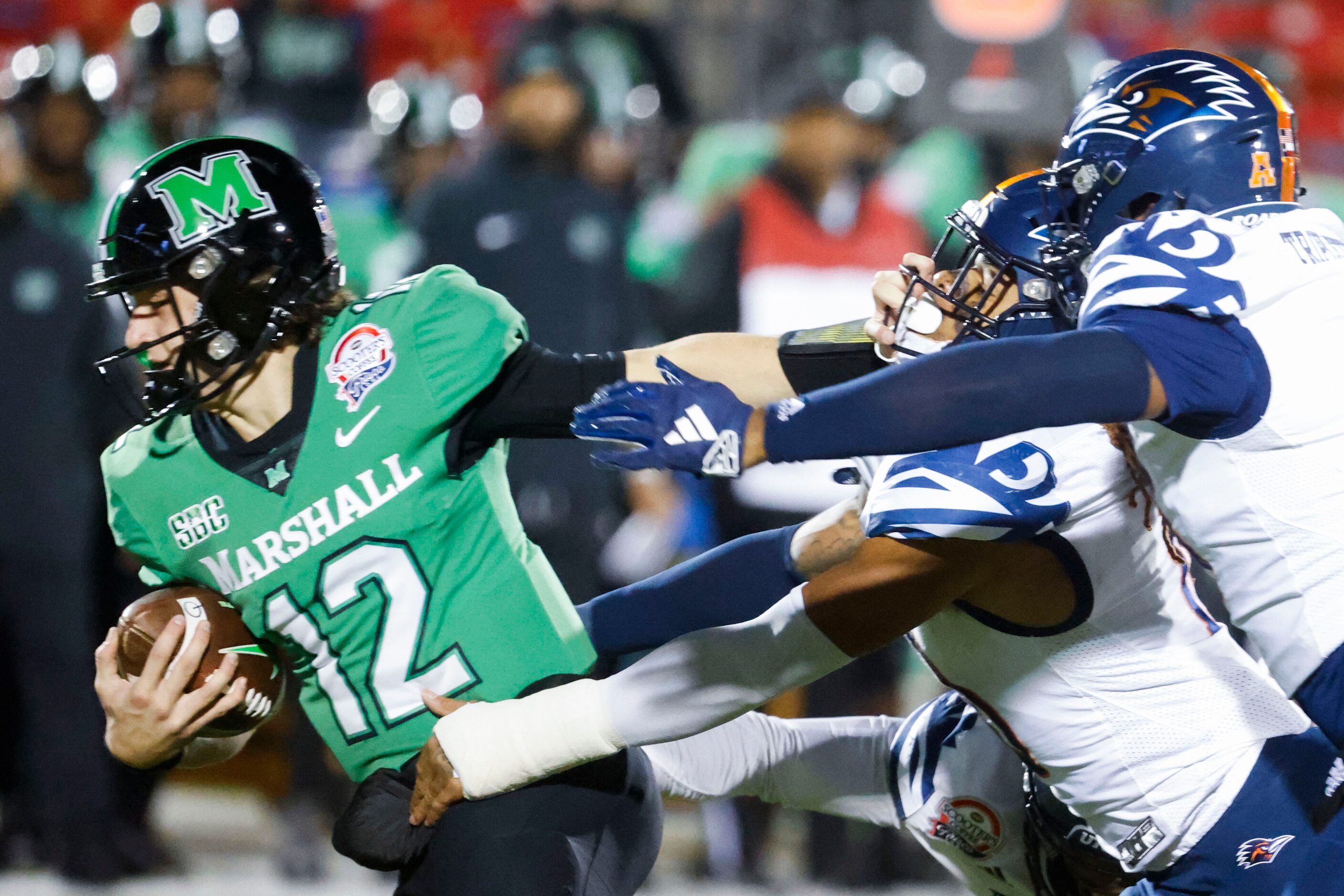 Marshall quarterback Cole Pennington (left) stiff arms as he gets sacked by UTSA linebacker...