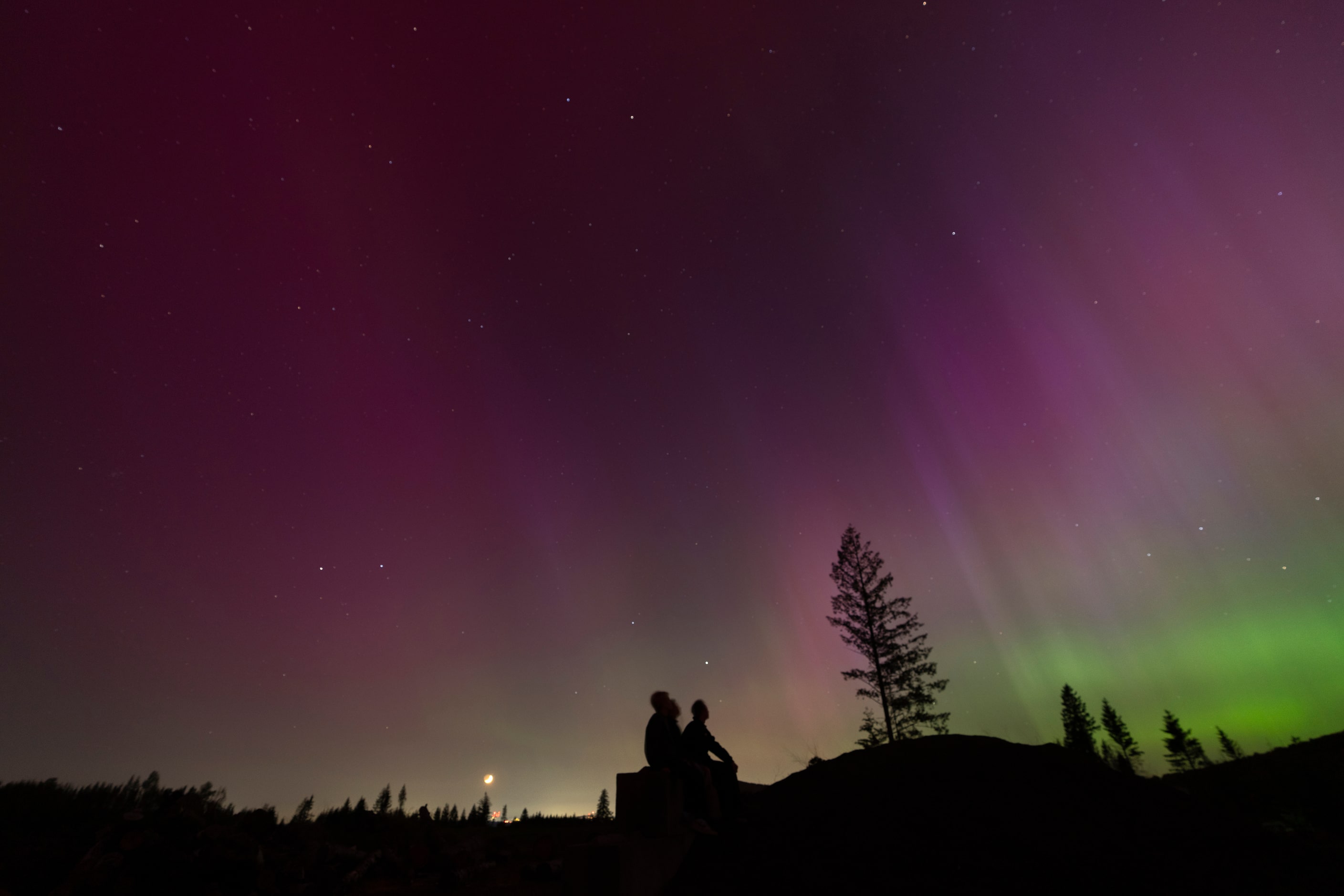 In this image taken with a long exposure, people look at the night sky towards the northern...