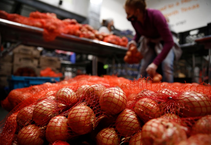 Lilly Gusqusquieta of Dallas works on sorting onions to put in bags  in the produce area at...