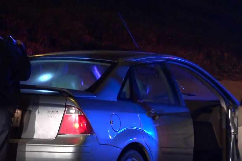A Dallas police officer examines a car that was burglarized then abandoned on the road near...