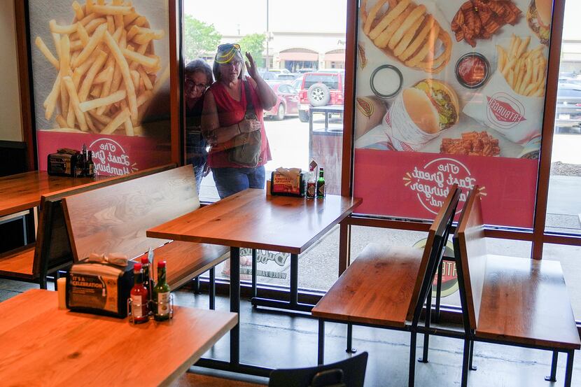 People peek through the windows of Fatburger to see if the restaurant is open at the Allen...