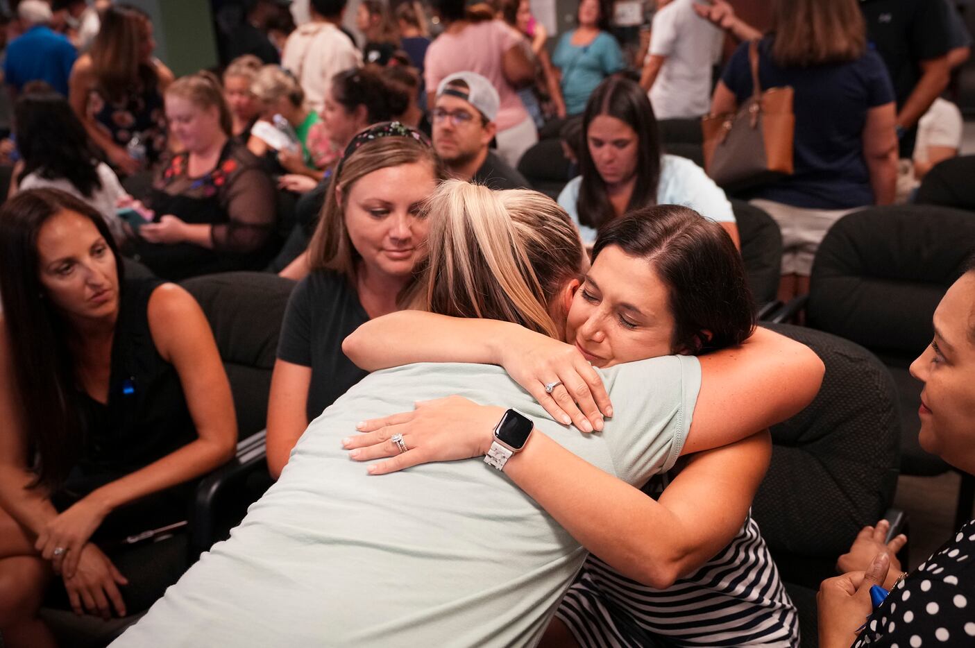 Lisa Cox (facing) gets a hug of support after speaking during public comment in a Prosper...