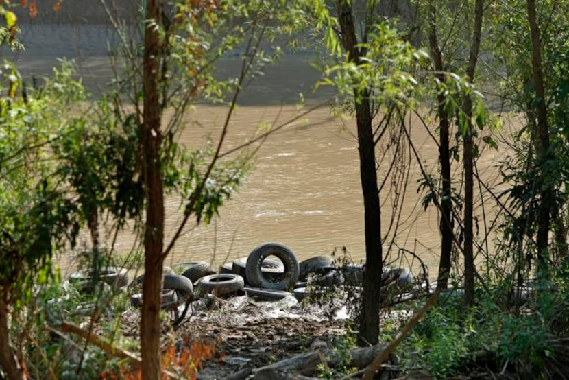 
Tires await removal from the bank of the Trinity, where relatively low water levels have...