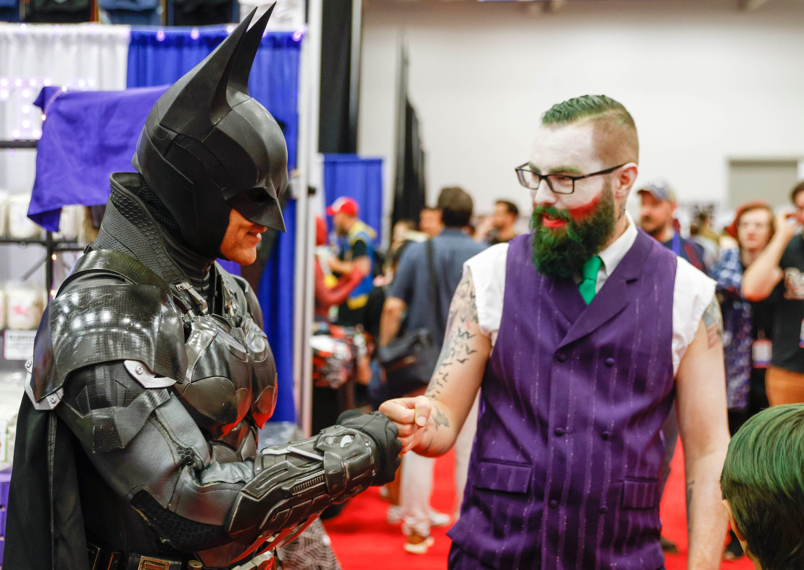 Will Ellis (left) dressed as Batman fist bumps Jason Walter, dressed as the Joker, during...