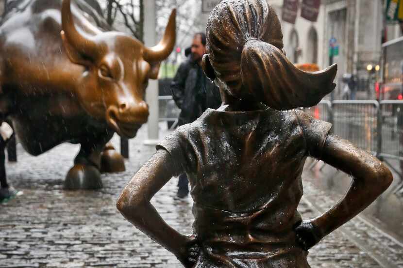 The "Fearless Girl" statue, created by Kristen Visbal, stands across from the "Charging...
