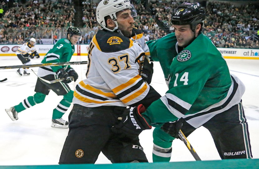 Dallas' Jamie Benn (14) and Boston's Patrice Bergeron (37) mix it up along the boards during...