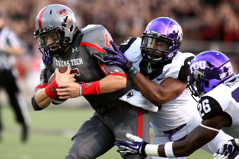 Texas Tech's Baker Mayfield, left, is tackled by TCU's Sam Carter, center, and Derrick...