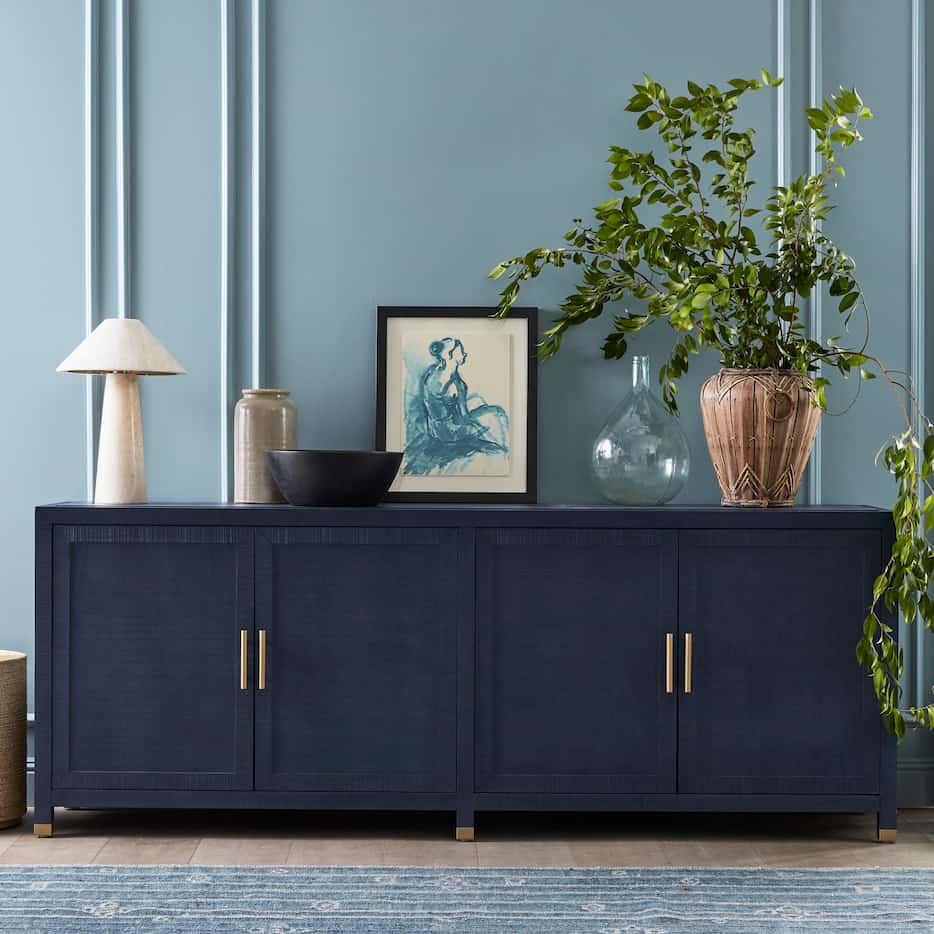 Sleek credenza topped with decor pieces against a blue wall